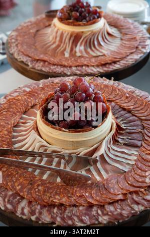 Elegante Charcuterie mit Wurstwaren und Trauben an Bord Stockfoto