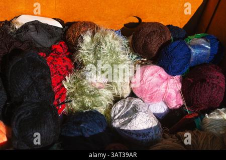 Vibrant assortment of yarn balls in various colors arranged together in box. Mix of textures and shades creates a delightful visual for crafting Stockfoto