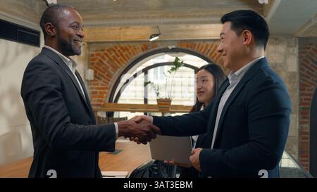 Drei multirassische Kollegen Kollegen Geschäftsleute sprechen im Büro afroamerikanischer Geschäftsmann Investor sprechen mit Asiaten Stockfoto