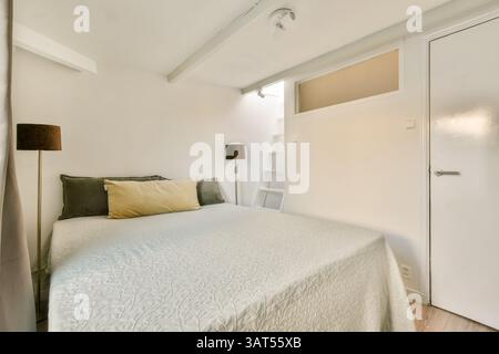 Ein wunderschön gestaltetes, modernes Schlafzimmer mit weicher Bettwäsche, minimalistischer Einrichtung und viel Tageslicht für eine entspannte Atmosphäre. Stockfoto
