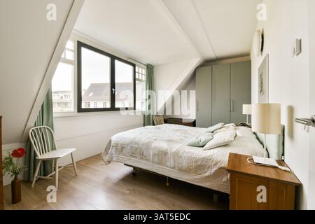 Ein wunderschön gestaltetes, modernes Schlafzimmer mit gemütlichem Bett, natürlichem Licht durch große Fenster und minimalistischer Einrichtung für eine ruhige Atmosphäre. Stockfoto