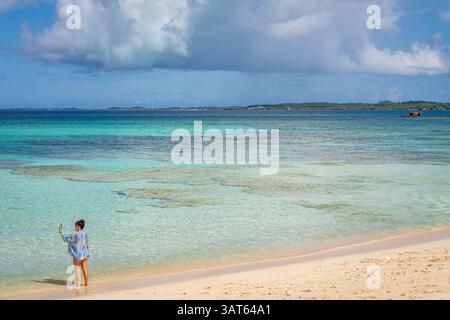 Frau macht Selfie am Strand von Okinawa und fängt das türkisfarbene Wasser und den sonnigen Himmel ein. Stockfoto