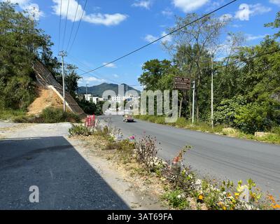 Ein malerischer Blick auf eine Straße durch eine lebendige natürliche Landschaft an einem sonnigen Tag. Stockfoto