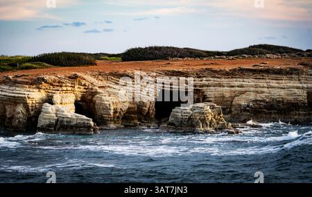 Felsige Küstenlandschaft mit Meereshöhlen und Wellen, die gegen die Küste krachen. Stockfoto