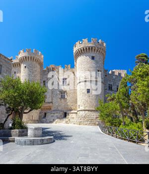 Ein sonniges, flaches Bild fängt die Steinfassade und die runden Türme des Palastes des Großmeisters der Ritter von Rhodos unter einem klaren blauen Himmel ein. Stockfoto