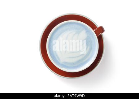 Leckerer blauer Matcha Latte mit Schaum in der Tasse auf roter Platte weißem Hintergrund Stockfoto