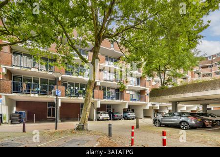 Ein modernes, städtisches Wohngebäude, das sich durch eine Mischung aus Grün und Architektur auszeichnet, mit geparkten Autos und einer lebhaften Nachbarschaftsatmosphäre. Stockfoto