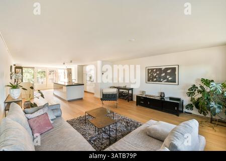 Geräumiges Wohnzimmer mit modernen Möbeln, üppigem Grün und viel Tageslicht für eine ruhige und einladende Atmosphäre. Stockfoto