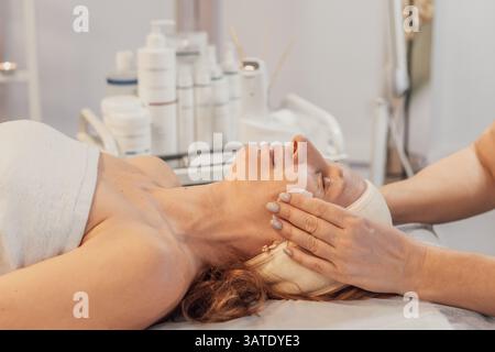 Frau genießt eine entspannende Gesichtsbehandlung im Spa Stockfoto