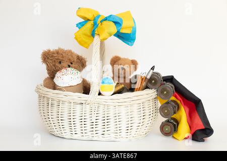 Osterkorb mit Bären und Fahnen Deutschlands und der Ukraine und Kugeln und Granatwerfer Patronen auf weißem Hintergrund, Ostern in der Ukraine Stockfoto