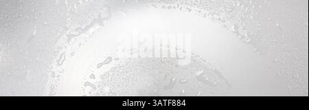Wischen Sie die Glasscheibe mit einem Glasreiniger und einem Gummiabzieher ab. Hygiene, Wassertropfen oder Spritzer, Flecken Desinfektion auf einer klaren Oberfläche. Stockfoto