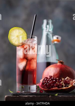 Granatapfelsaft mit Eis im Glas und Obst auf dem Tisch Stockfoto