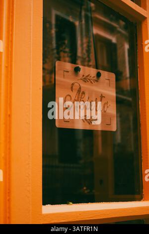 Madrid, Spanien 1. Mai 2024 Ein hölzernes Schild im Fenster mit der Aufschrift „Aberto“ (auf Portugiesisch, Spanisch geöffnet), das von einem orangen Gebäude umgeben ist, das bereit ist für den Geschäftsbetrieb Stockfoto