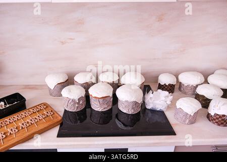 Moskau, Russland, 18.04.25. Ein Tisch mit einem Haufen Cupcakes und einer Schachtel mit Zahlen drauf. Die Cupcakes sind alle weiß und haben eine Zuckerguss Stockfoto