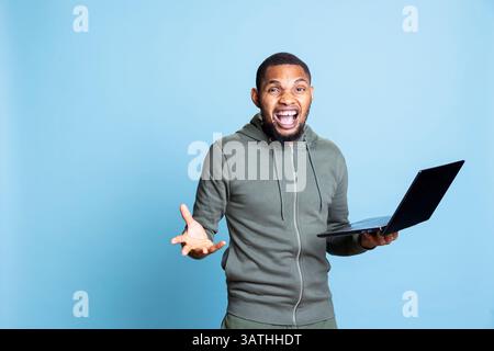 Positiver, fröhlicher afroamerikaner, der mit seinen Freunden auf Video diskutiert, mit seinen Freunden plaudert und tratscht. Junger Erwachsener war mit seinem Online-Telefonkonferenztreffen zufrieden. Stockfoto