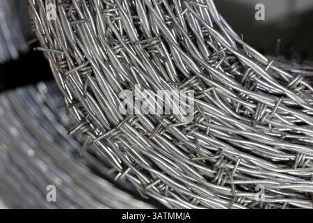 Nahaufnahme einer Stapelrolle aus glänzendem neuem Stacheldraht. Stockfoto