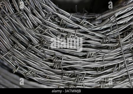 Nahaufnahme einer Stapelrolle aus glänzendem neuem Stacheldraht. Stockfoto