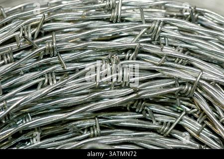 Nahaufnahme einer Stapelrolle aus glänzendem neuem Stacheldraht. Stockfoto