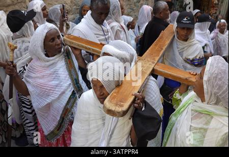 JERUSALEM – 18. APRIL: Äthiopisch-orthodoxe Christen tragen ein großes Holzkreuz bei einem Spaziergang entlang der Via Dolorosa in der Altstadt während der Karfreitagsprozession am 18. April 2025 in Jerusalem, Israel. Christen feiern Karfreitag, um der Kreuzigung Jesu und seinem Tod am Kreuz zu gedenken. Stockfoto