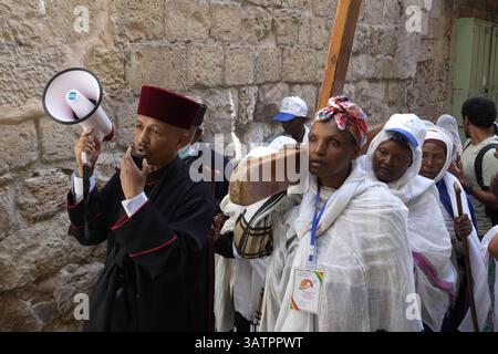JERUSALEM – 18. APRIL: Äthiopisch-orthodoxe Christen tragen ein großes Holzkreuz bei einem Spaziergang entlang der Via Dolorosa in der Altstadt während der Karfreitagsprozession am 18. April 2025 in Jerusalem, Israel. Christen feiern Karfreitag, um der Kreuzigung Jesu und seinem Tod am Kreuz zu gedenken. Stockfoto