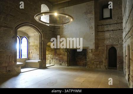 Leerer Raum im mittelalterlichen Königspalast von Olith in navarra, spanien, mit großem Kamin, Buntglasfenstern und einem modernen runden Chandeli Stockfoto