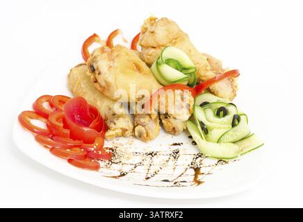 Gebratene Hähnchenschenkel, serviert mit rotem Pfeffer und Gurke Stockfoto