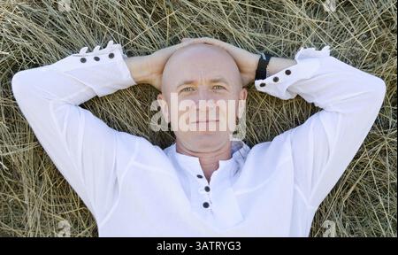 Ein kaukasier in einem weißen Hemd lächelt auf Heu Stockfoto