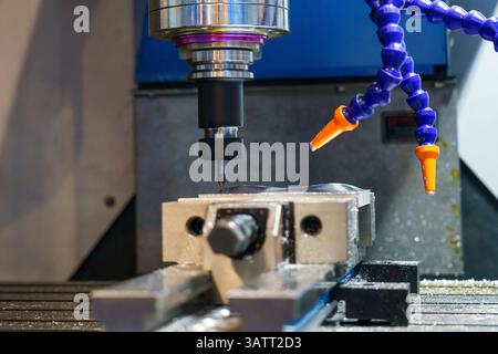 Die CNC-Fräsmaschine bohrt das Metallteil mit flachen Bohrwerkzeugen. Der Fertigungsbetrieb mit NC-Fräsmaschine. Stockfoto
