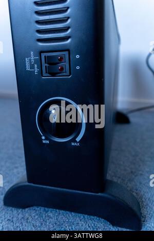 Seitenansicht der kleinen elektrischen Raumheizung im Haus. Dies ist ein Konvektionsheizer für den Einsatz in einem kleinen Raum und wird an der Wand angeschlossen. Stockfoto
