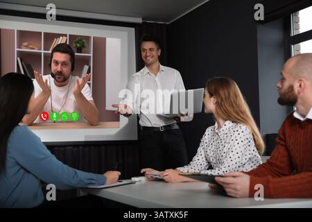 Redner, der über Online-Videochat an der Vorlesung teilnimmt. Publikum und Trainer im Konferenzraum mit Projektionsleinwand Stockfoto