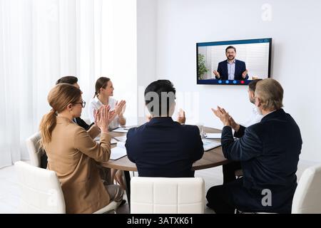 Redner, der über Online-Videochat an der Vorlesung teilnimmt. Publikum im Konferenzraum mit Fernseher Stockfoto