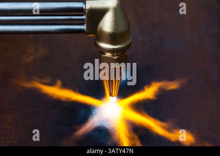 Gasschneiden von Metall. Gasschneider mit Kupferdüse mit einem auf das Metall gerichteten Brandstrahl. Erhitzen des Metalls mit einem Gasschneider. Stockfoto