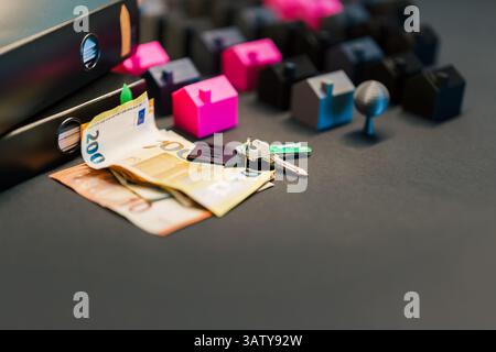 Nahaufnahme von Hausschlüsseln, Euro-Banknoten und Ordnern mit Dokumenten auf einem Schreibtisch neben einem Miniatur-Wohnbaumodell. Dieses konzeptionelle Bild repräsentiert Stockfoto