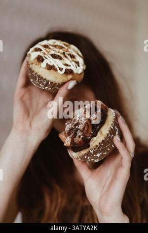 Frau hält köstliche süße Cupcakes mit Buttercreme und Keksen, köstliches Dessertkonzept Stockfoto