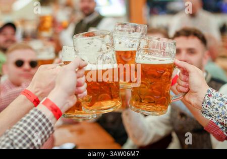 Stuttgart, Deutschland. April 2025. Besucher der 85. Stuttgarter Frühlingsfestspiele zwitschern ihre Bierbecher in einem Festzelt. Das 85. Stuttgarter Frühlingsfest findet vom 19. April bis 11. Mai 2025 im Cannstatter Wasen statt. Quelle: Christoph Schmidt/dpa/Alamy Live News Stockfoto