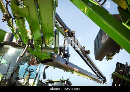 John Deere Landwirtschaftsspritze mit grünem Metallrahmen, Hydraulikkomponenten und Spritzbalken. Stockfoto