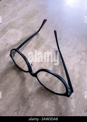Eine Brille mit schwarzem Rand sitzt auf einem Tisch Stockfoto