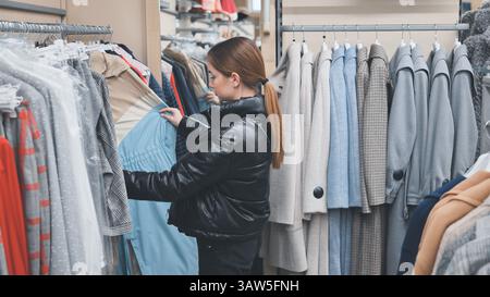 Modebewusste Shopper durchsuchen die Kleiderständer, untersuchen sorgfältig trendige Kleidungsstücke und wählen stilvolle Garderobe Stockfoto