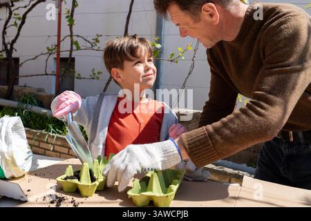 Öko-Gartenarbeit mit Kind: Saatgut in Eischachteln im Freien Pflanzen Stockfoto