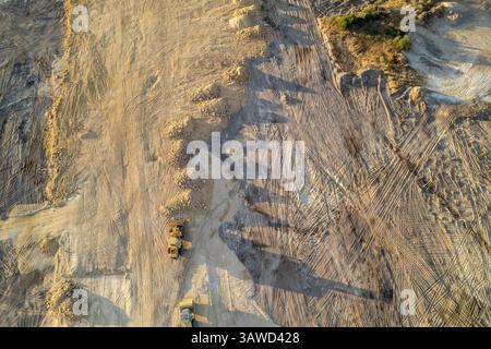 Bagger, die von oben auf einer unfruchtbaren Baustelle arbeiten. Stockfoto
