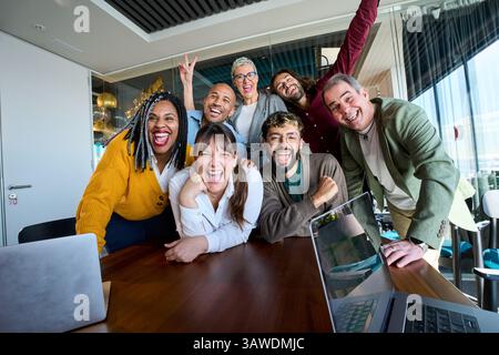Verschiedene Kollegen lachen bei einem fröhlichen Büromeeting zusammen Stockfoto