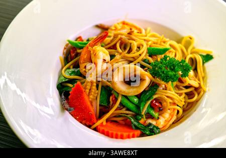 Schließen Sie die Fusion-Küche aus thailändischem und italienischem Stil, Spaghetti Pad Kee Mao Ta Lay oder gebratene Spaghetti mit scharfen thailändischen Kräutern und Meeresfrüchten. Nahaufnahme Stockfoto