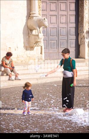 Mutter und Kind vor der Päpstlichen Basilika St. Nikolaus in Bari, Apulien, Süditalien. Die Kirche hat eine große religiöse Bedeutung in ganz Europa und der christlichen Welt und ist ein wichtiges Pilgerziel sowohl für Katholiken als auch für orthodoxe Christen. Die Basilika wurde zwischen 1087 und 1197 während der italienisch-normannischen Herrschaft Apuliens erbaut. Stockfoto