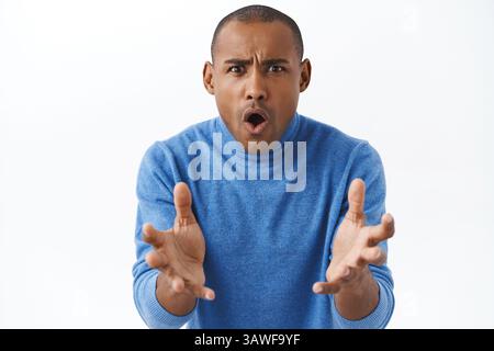 Wie geht es Ihnen? Porträt eines frustrierten, aufgebrachten und schockierten jungen afroamerikanischen Mannes, der die Hände nach vorne greift, Arme schüttelt und aufschäumt, wütend darüber Stockfoto