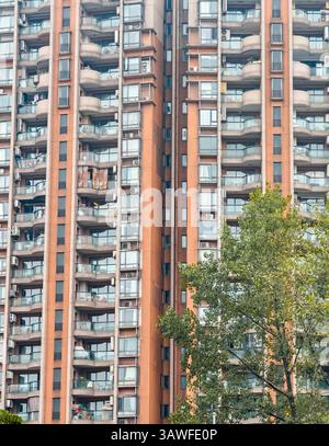 Modernes Wohngebäude mit Balkonen und Klimaanlage in einem belebten Stadtgebiet. Stockfoto