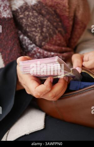 Person, die einen Stapel Dokumente hält, während sie an einem öffentlichen Platz sitzt Stockfoto
