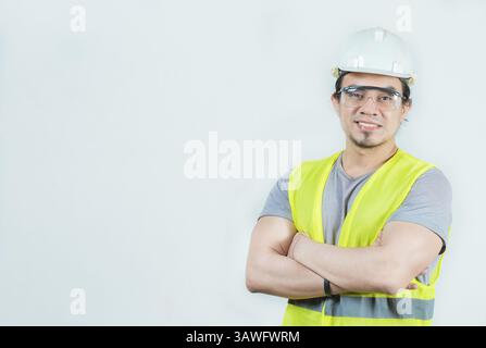 Porträt eines lächelnden lateinischen Ingenieurs mit gekreuzten Armen. Junger latein-Ingenieur mit Helm und Weste isoliert Stockfoto