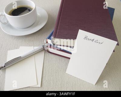 Ein Stapel Bücher, eine Liste mit Büchern und eine Tasse Stockfoto
