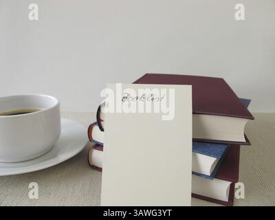 Ein Stapel Bücher, eine Liste mit Büchern und eine Tasse Stockfoto