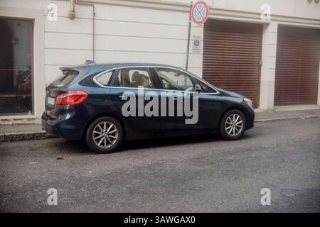 Cremona, Italien, 15. März 2025 Dunkelblauer BMW 2er Active Tourer parkte in der Nähe eines Verkehrsschilds ohne Parken und vor einem geschlossenen Garagentor in einer EU Stockfoto